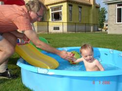 Félix glisse dans la piscine avec l'aide de  son grand-papa.
